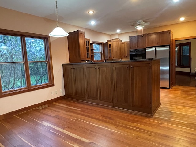 kitchen with dark countertops, a peninsula, oven, and freestanding refrigerator