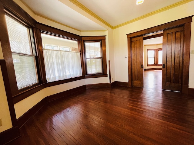 unfurnished room with ornamental molding, dark wood-style floors, and baseboards