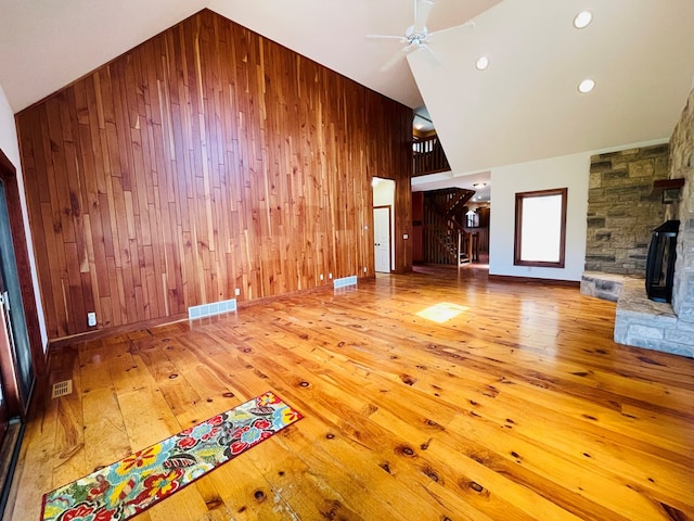 unfurnished living room featuring wood walls, visible vents, and hardwood / wood-style floors