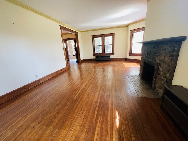 unfurnished living room with baseboards, ornamental molding, hardwood / wood-style flooring, and a fireplace