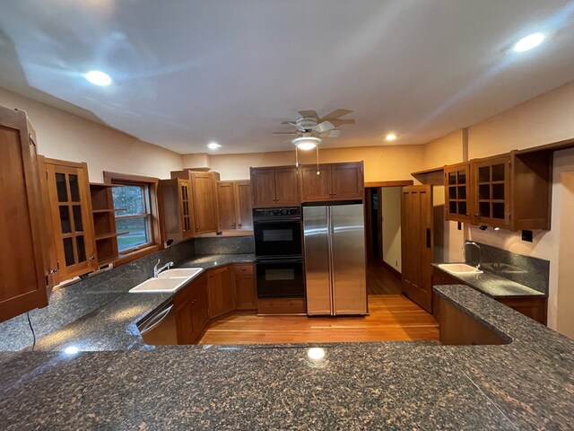 kitchen featuring open shelves, glass insert cabinets, appliances with stainless steel finishes, and a sink