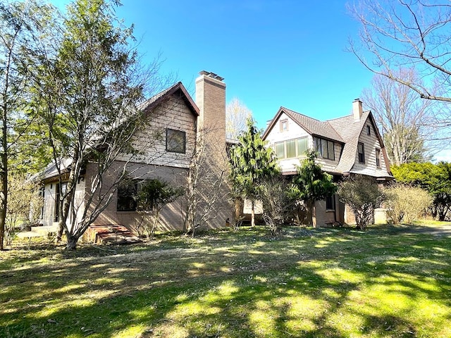 back of property with a chimney and a yard