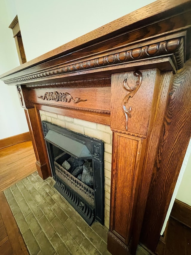 details featuring baseboards, wood finished floors, and a glass covered fireplace