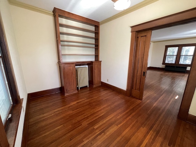 spare room featuring dark wood finished floors, baseboards, radiator, and crown molding