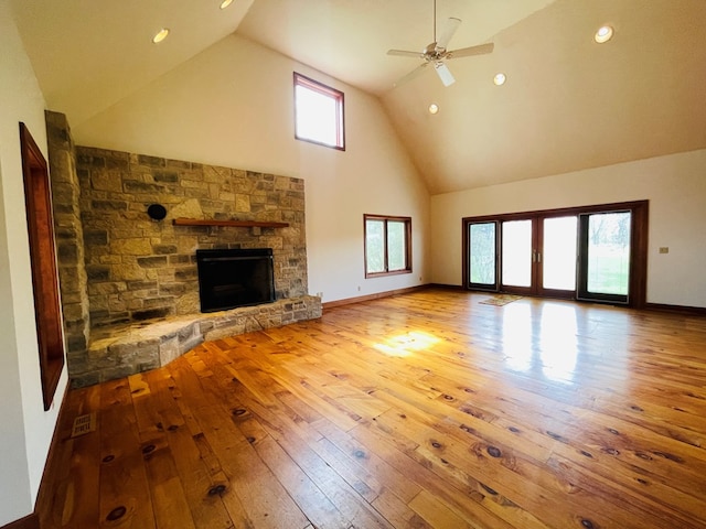 unfurnished living room featuring recessed lighting, high vaulted ceiling, a ceiling fan, a stone fireplace, and hardwood / wood-style floors