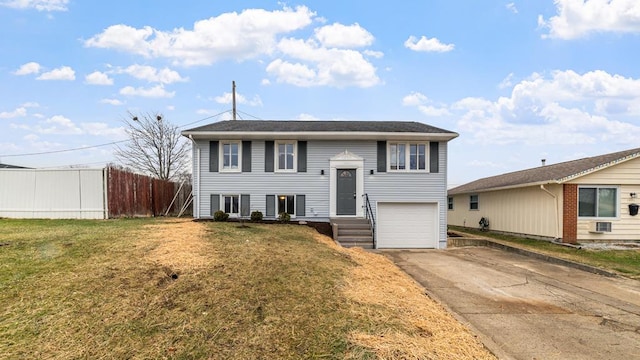 bi-level home featuring a garage, driveway, a front lawn, and fence