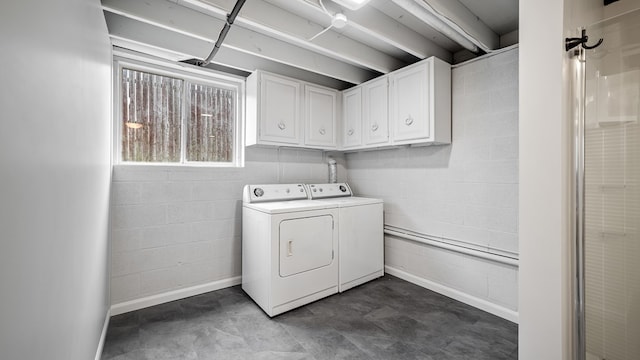 washroom with independent washer and dryer, concrete block wall, cabinet space, and baseboards