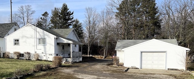 view of side of home featuring a garage, driveway, a lawn, and an outdoor structure