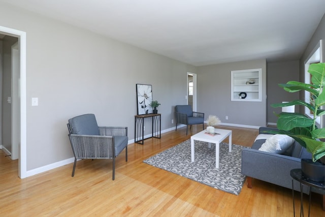 living room with baseboards, wood finished floors, and built in shelves