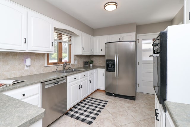 kitchen featuring white cabinets, a sink, backsplash, appliances with stainless steel finishes, and light tile patterned floors