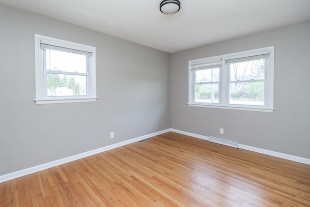 unfurnished room with visible vents, light wood-style flooring, and baseboards