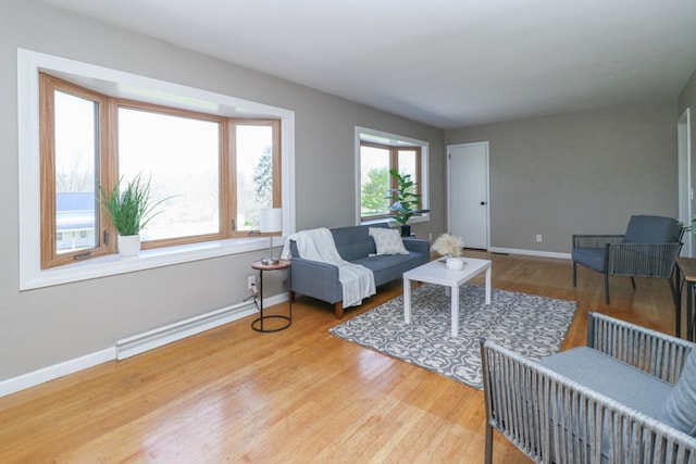 living room featuring a baseboard heating unit, baseboards, and wood finished floors
