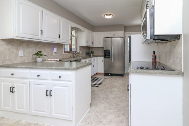 kitchen with stainless steel appliances, a sink, decorative backsplash, a peninsula, and white cabinetry