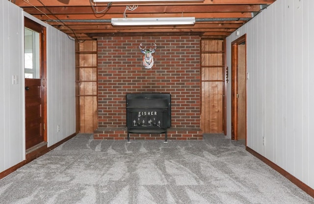 unfurnished living room with wooden walls, baseboards, carpet, and a fireplace