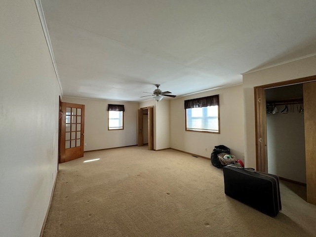 interior space with plenty of natural light, ceiling fan, crown molding, and light carpet