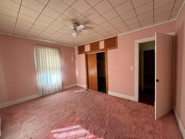 unfurnished bedroom with carpet, a closet, crown molding, and ceiling fan