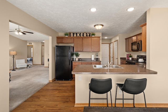 kitchen with ceiling fan, a sink, a textured ceiling, a peninsula, and black appliances