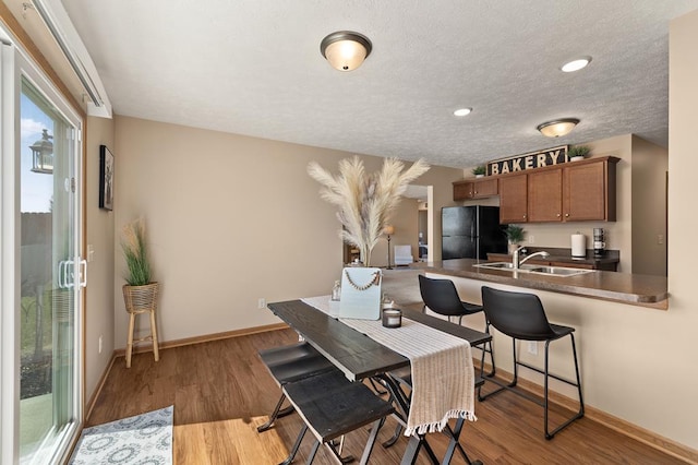 dining area featuring baseboards, a textured ceiling, and light wood-style floors