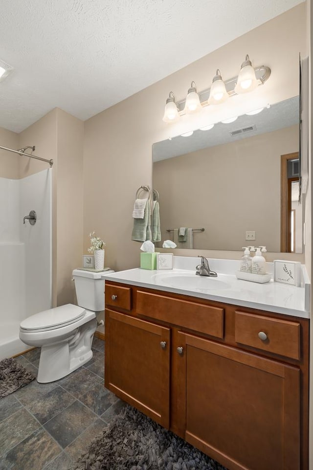 bathroom featuring stone finish flooring, visible vents, a shower, vanity, and toilet