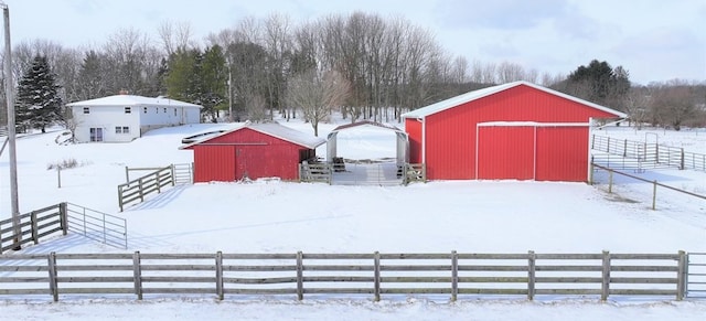 snowy yard featuring a rural view and an outdoor structure