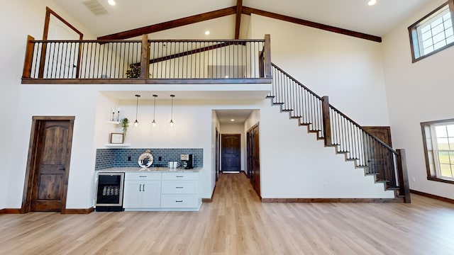 bar featuring pendant lighting, high vaulted ceiling, white cabinets, wine cooler, and decorative backsplash