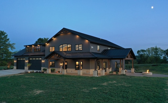 modern farmhouse with a standing seam roof, driveway, a fire pit, and a yard