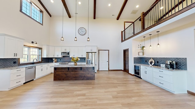 kitchen featuring beamed ceiling, a high ceiling, stainless steel appliances, and wine cooler