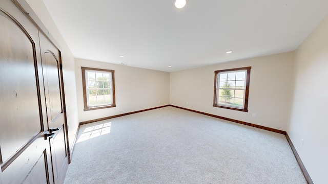 unfurnished bedroom featuring light carpet and multiple windows