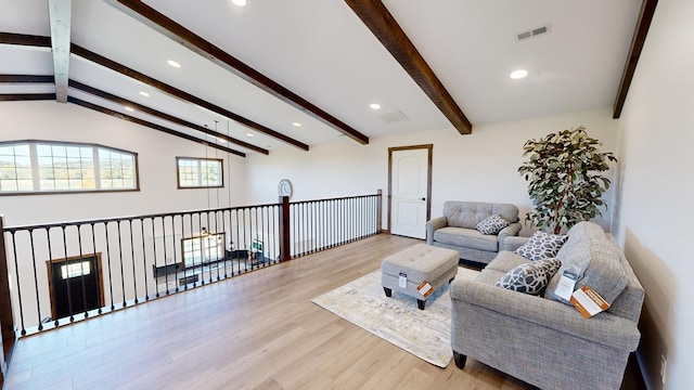 living room featuring vaulted ceiling with beams and light hardwood / wood-style floors