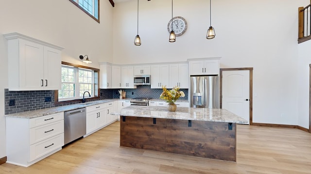 kitchen with decorative light fixtures, a center island, white cabinetry, and appliances with stainless steel finishes