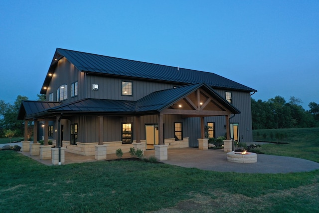 back house at dusk with a patio area, a yard, and an outdoor fire pit