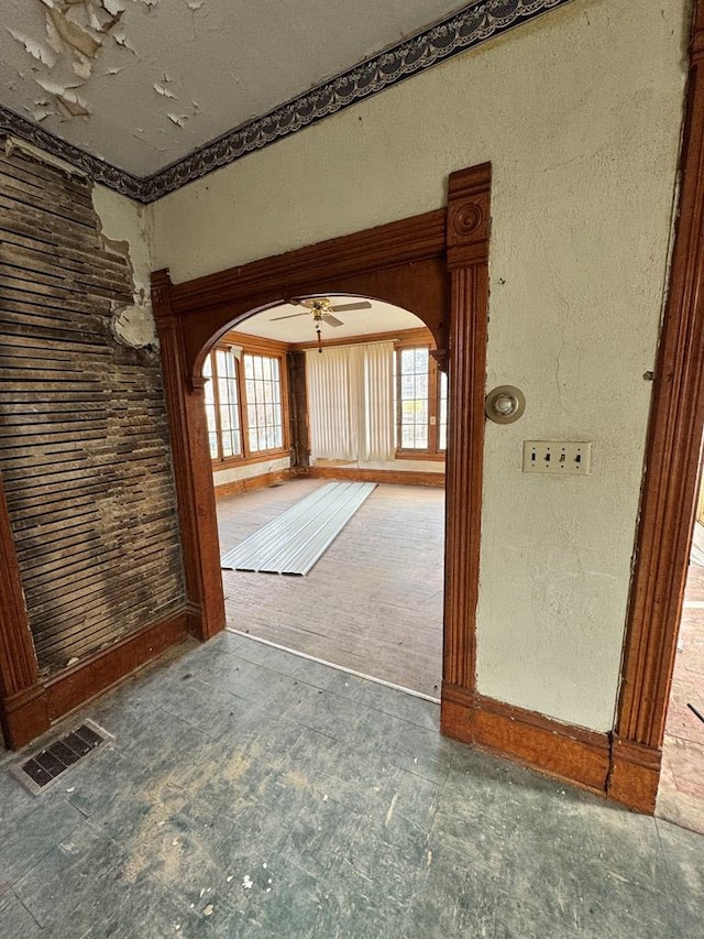 unfurnished room with arched walkways, visible vents, and a textured wall