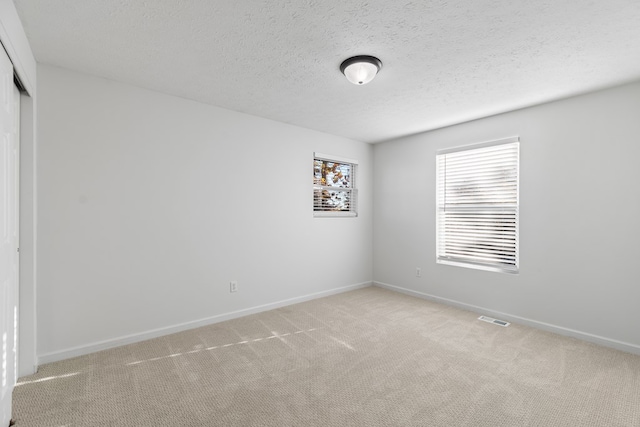 unfurnished room featuring light carpet and a textured ceiling