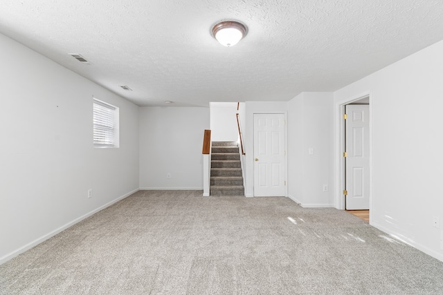 unfurnished room with light carpet and a textured ceiling