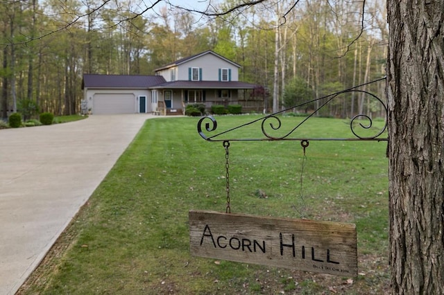 view of front of house with covered porch, driveway, a garage, a view of trees, and a front lawn