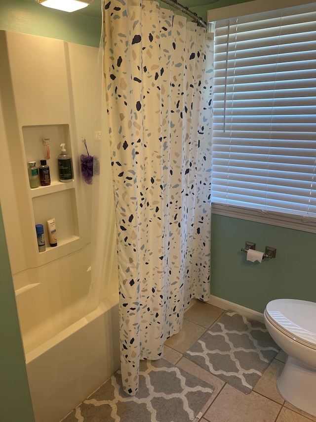 full bathroom featuring tile patterned floors, baseboards, toilet, and shower / bath combo