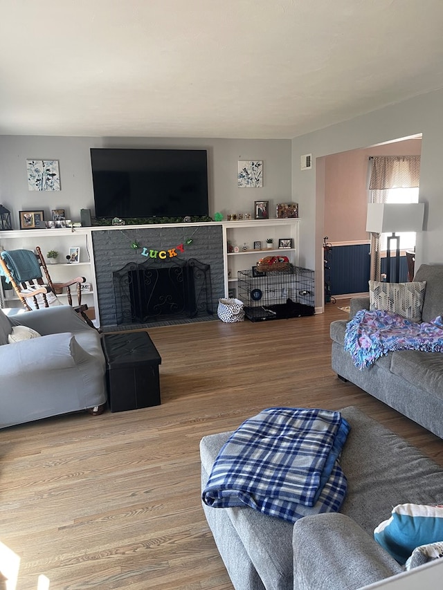 living area with wood finished floors, a fireplace, and visible vents