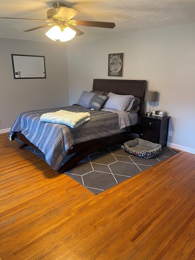 bedroom with ceiling fan, baseboards, and wood finished floors