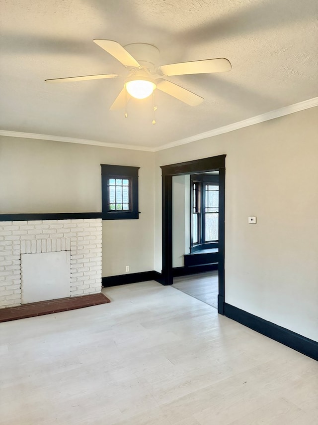 unfurnished room featuring ornamental molding, ceiling fan, a textured ceiling, and a fireplace