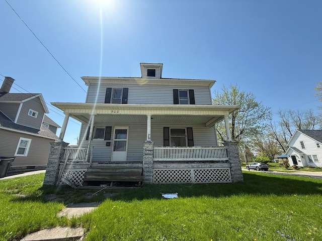 traditional style home featuring covered porch and a front yard