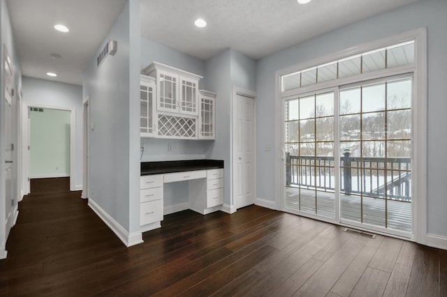 unfurnished office featuring built in desk and dark wood-type flooring