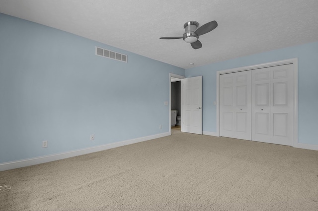 unfurnished bedroom with a textured ceiling, a closet, ceiling fan, and carpet floors