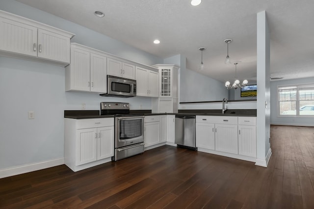 kitchen with appliances with stainless steel finishes, decorative light fixtures, an inviting chandelier, white cabinets, and dark hardwood / wood-style floors