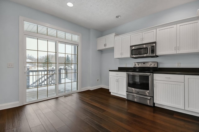 kitchen with white cabinets, a textured ceiling, stainless steel appliances, and dark wood-type flooring