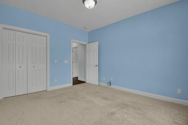 unfurnished bedroom with carpet, a textured ceiling, and a closet