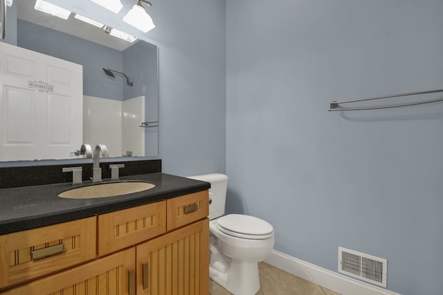 bathroom featuring tile patterned floors, toilet, vanity, and walk in shower