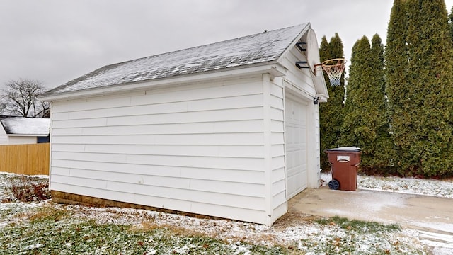 view of snow covered exterior featuring a garage and an outdoor structure