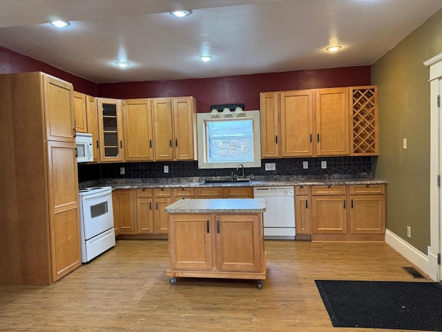 kitchen featuring a kitchen island, sink, light wood-type flooring, decorative backsplash, and white appliances