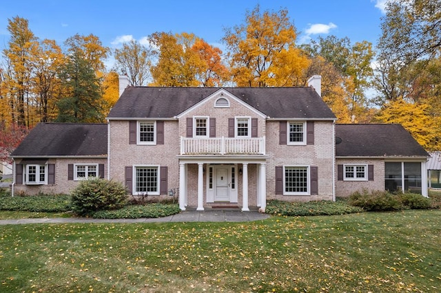 colonial-style house with a front yard, a porch, and a balcony