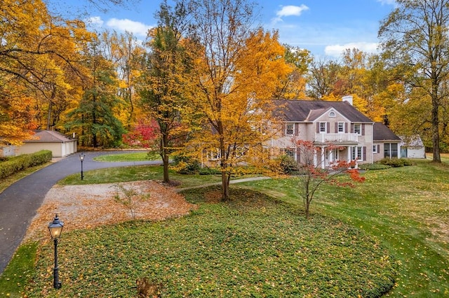 view of front of house featuring a balcony, an outdoor structure, and a front lawn